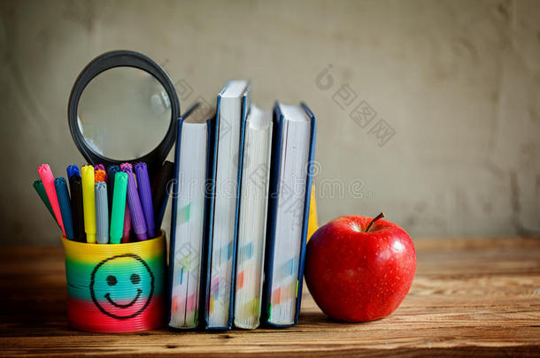 一组学习用品和书籍以及背景上的红苹果。学校，文具，设备。