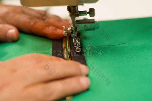 关闭缝纫机与棕色拉链在绿色织物上，手帮助
