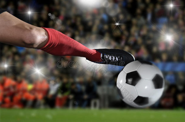 关闭足球运动员的腿和足球鞋在行动踢球在体育场比赛