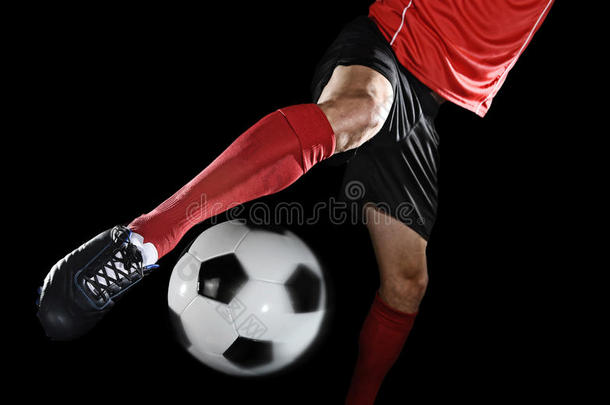 关闭足球运动员的腿和足球鞋在动作踢球隔离在黑色背景