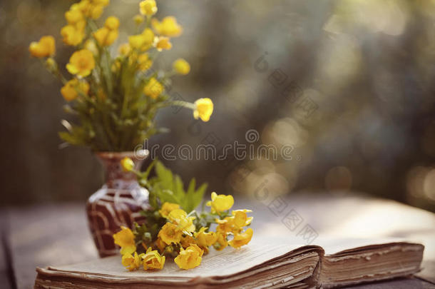 一束黄油杯和桌子上的旧公开书。