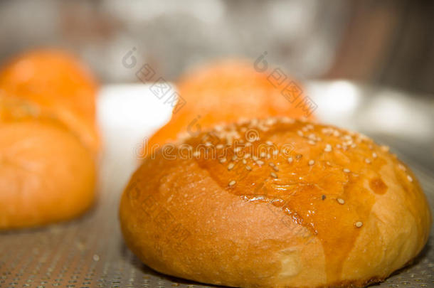 特写新鲜烤面包包子与芝麻顶部，坐在灰色的烹饪表面