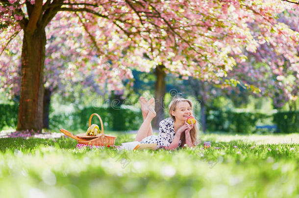 美丽的年轻女人在盛开的春天公园野餐