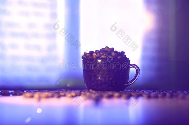 装满咖啡豆的咖啡杯。 一杯咖啡。 桌子上的咖啡豆。 模糊的背景