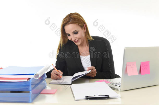 女商人在笔记本电脑办公桌上工作，在笔记本上记笔记
