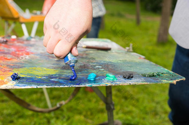 艺术家在调色板上挤压油漆