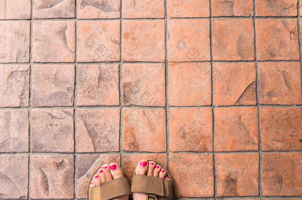 脚自拍从一个穿凉鞋的女旅行者在世界各地的旅游旅行的上部视图。 游客拍一张照片
