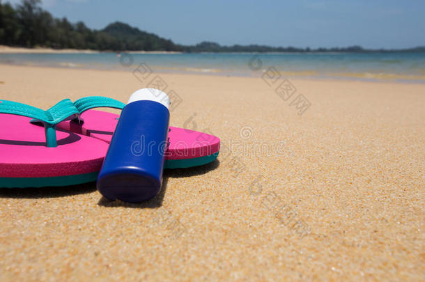 海滩上的沐浴液和粉红色拖鞋