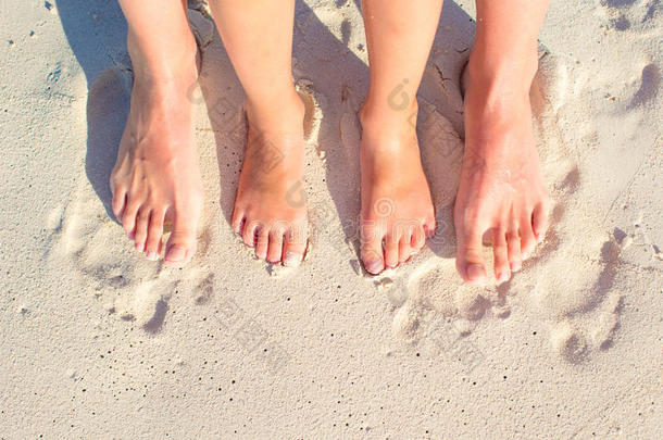 特写母亲和孩子的脚在白沙滩上