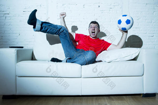 疯狂的狂热男子作为足球迷在电视上观看比赛，穿着红队球衣庆祝进球