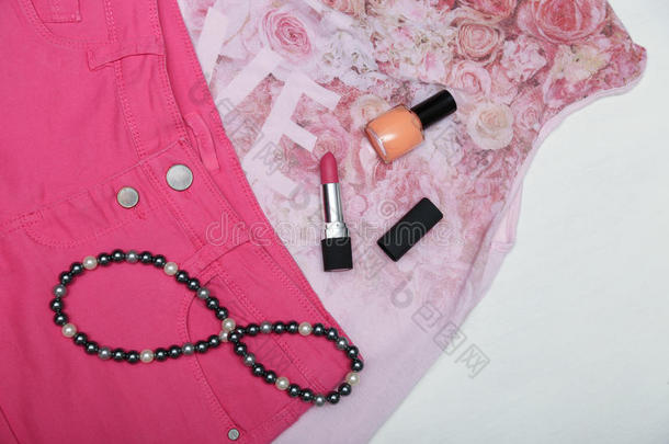 女孩配饰口红，指甲油和项链在粉红色的衣服上