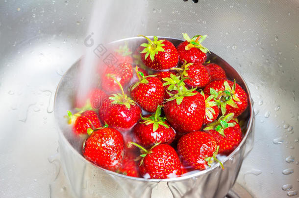 一碗有机草莓在流水下的水槽里