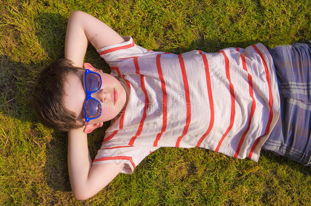 夏天带着太阳镜在草地上晒太阳的男孩