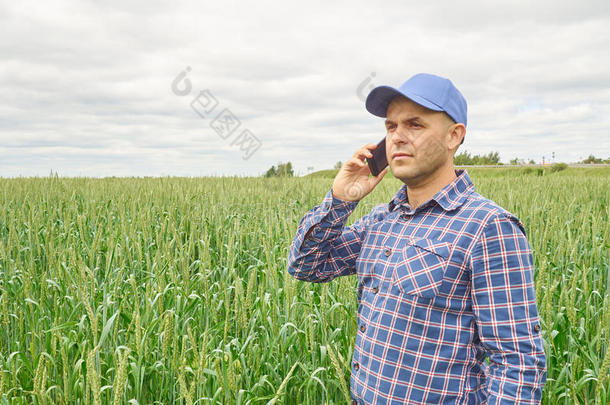 穿着格子衬衫的农民控制着他的田地。打电话。