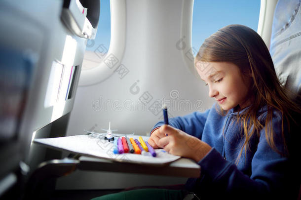 可爱的小女孩乘飞机旅行。 孩子坐在窗边画画。