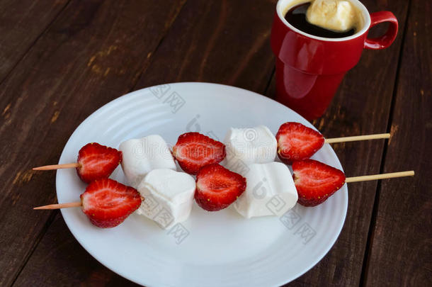 一杯咖啡和棉花糖配新鲜草莓串