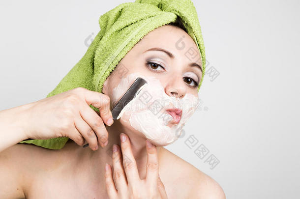 漂亮的年轻女人穿着<strong>浴巾</strong>，用直剃刀刮胡子。 美容行业和<strong>家居</strong>护肤理念