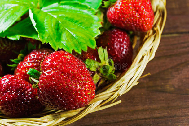 新鲜成熟的草莓在柳条篮子在旧的木制背景