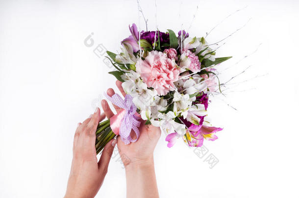 双手捧着一束粉红色和紫色的百合花和白底的花
