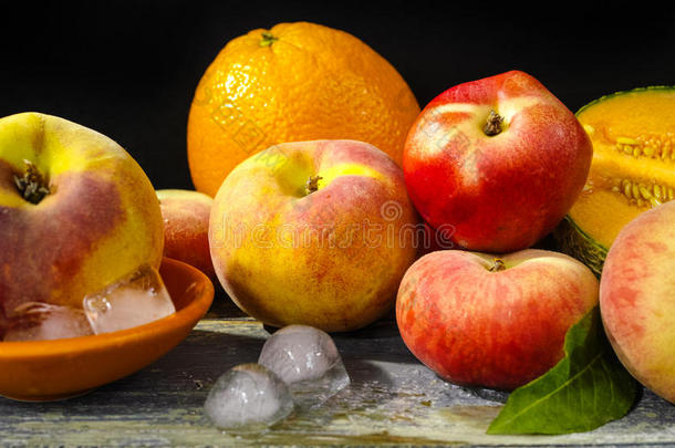 新鲜<strong>桃子</strong>，<strong>甜瓜</strong>和橘子在冰上，炎热的夏天概念