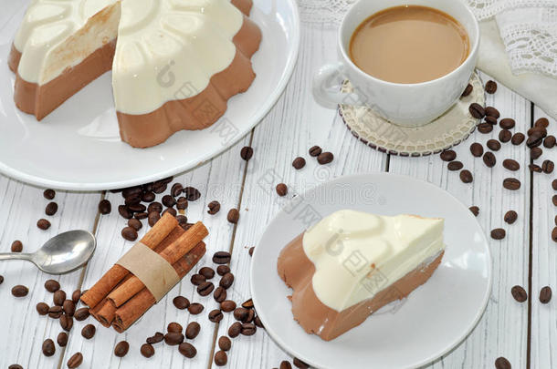 一种带有开胃慕斯层（香草和巧克力）蛋糕和一杯牛奶咖啡的盘子