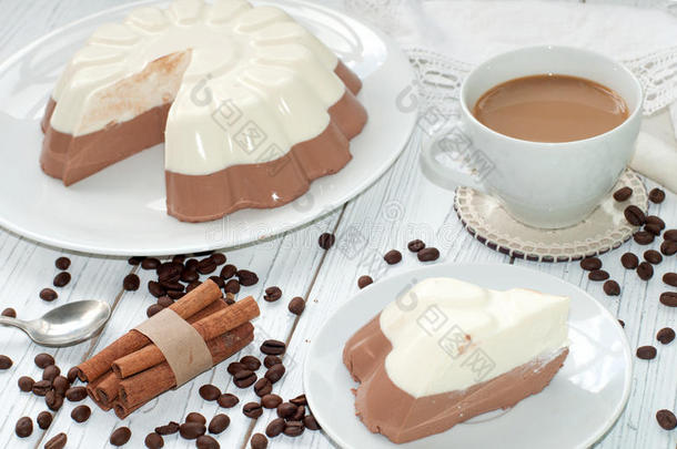 一种带有开胃慕斯层（香草和巧克力）蛋糕和一杯牛<strong>奶咖</strong>啡的盘子