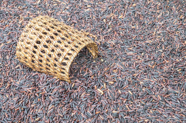 特写一堆黑米，称为杨梅米与木制柳条，大米与高营养在模糊的杨梅纹理巴