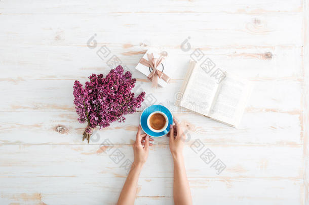 女人在桌子上喝咖啡和看书的手