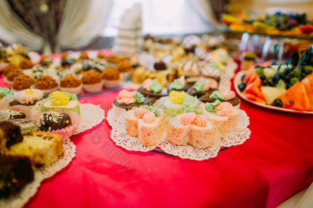 在豪华的派对餐厅背景下，在红色桌布上提供高级甜点自助餐