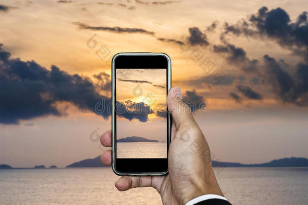 手持智能手机拍摄日落景观的垂直构图，在暑假时间