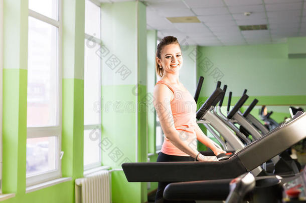 健身女孩在跑步机上跑步。 健身房里有肌肉腿的女人