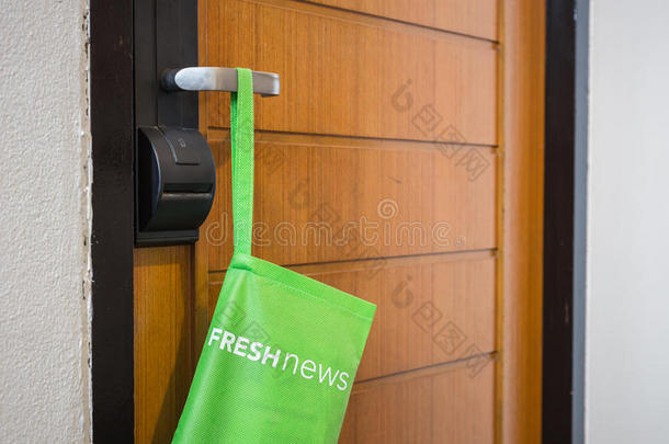 带报纸的绿色袋子挂在酒店的门上