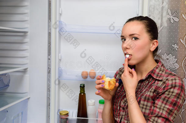 女孩在冰箱附近吃蛋糕