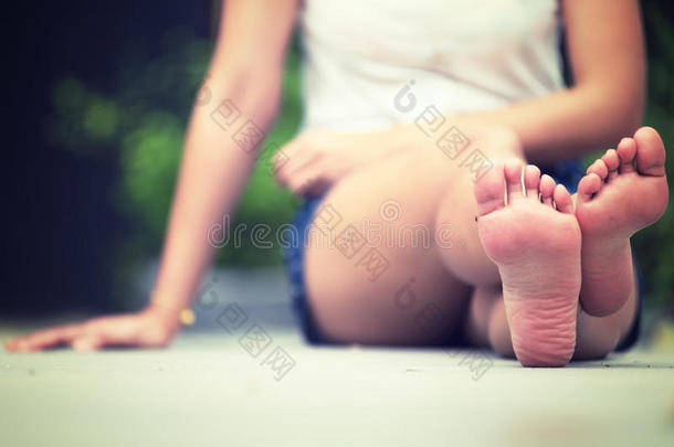 亚洲女人坐在地板上。 双脚靠近