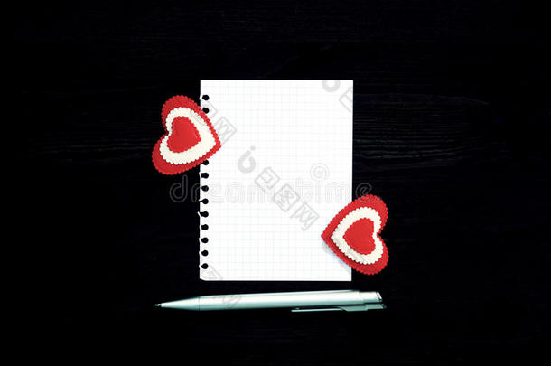木制背景上的一张白纸、钢笔和两颗心