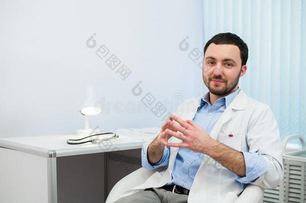 开朗的医生说话，看着镜头。 医生在坐在医院时与病人交谈。