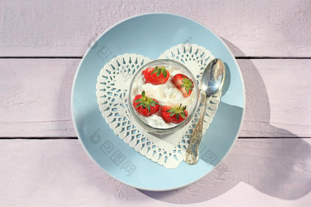新鲜草莓，水果酸奶和鲜奶油在浅粉色的木桌上