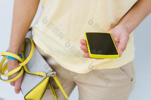 一个带着黄色手机和<strong>女包</strong>的女孩的特写