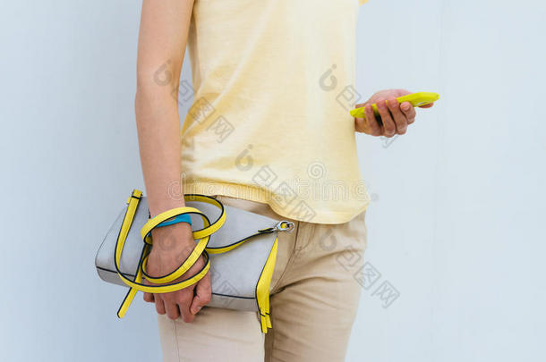 一个女人的特写，里面有一个黄色的手机和一个<strong>女包</strong>