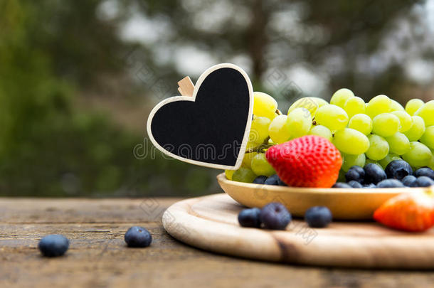 新鲜的时令水果放在木桌上的碗里，用心复制