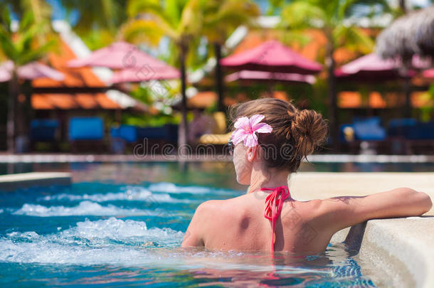 在豪华的热带游泳池里放松的比基尼女士的背景