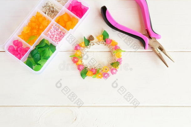 明亮美丽的手链，粉红色和黄色的丙烯酸珠子花和绿叶。 钳子
