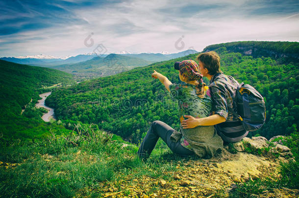 一对夫妇坐在边缘，看着山，女孩点，复古相机的效果