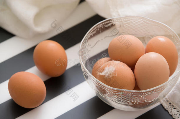 新鲜的<strong>浅棕色</strong>有机鸡蛋在一个烤碗准备复活节。 白<strong>色</strong>和黑<strong>色</strong>条纹作为鸡蛋的<strong>背景</strong>。