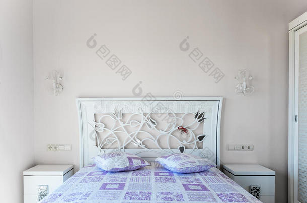 卧室里的床。 床头板和紫色垫子。 两个床边t