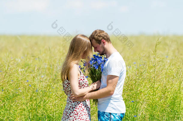 美丽的一对夫妇，捧着一束鲜花站在春天的草地上