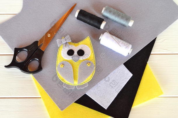 毛毡猫头鹰玩具。 毡片，剪刀，线，针，针-一套针线。 木制背景