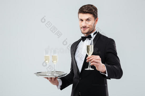 有吸引力的侍者穿着燕尾服，拿着托盘和一杯香槟