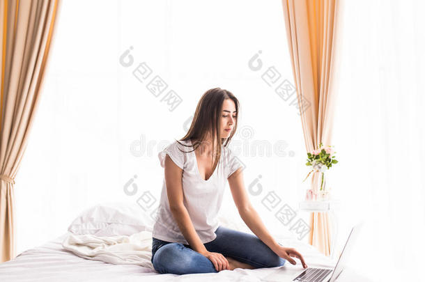 女孩躺在房间里的床上看着笔记本<strong>电脑显示器</strong>