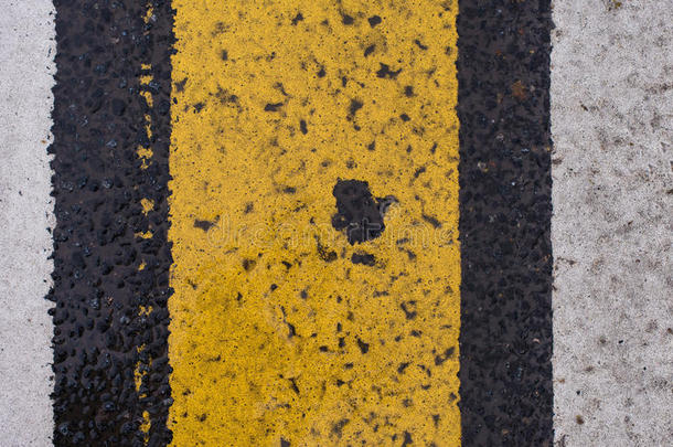 沥青公路纹理，有裂纹的白色和黄色条纹